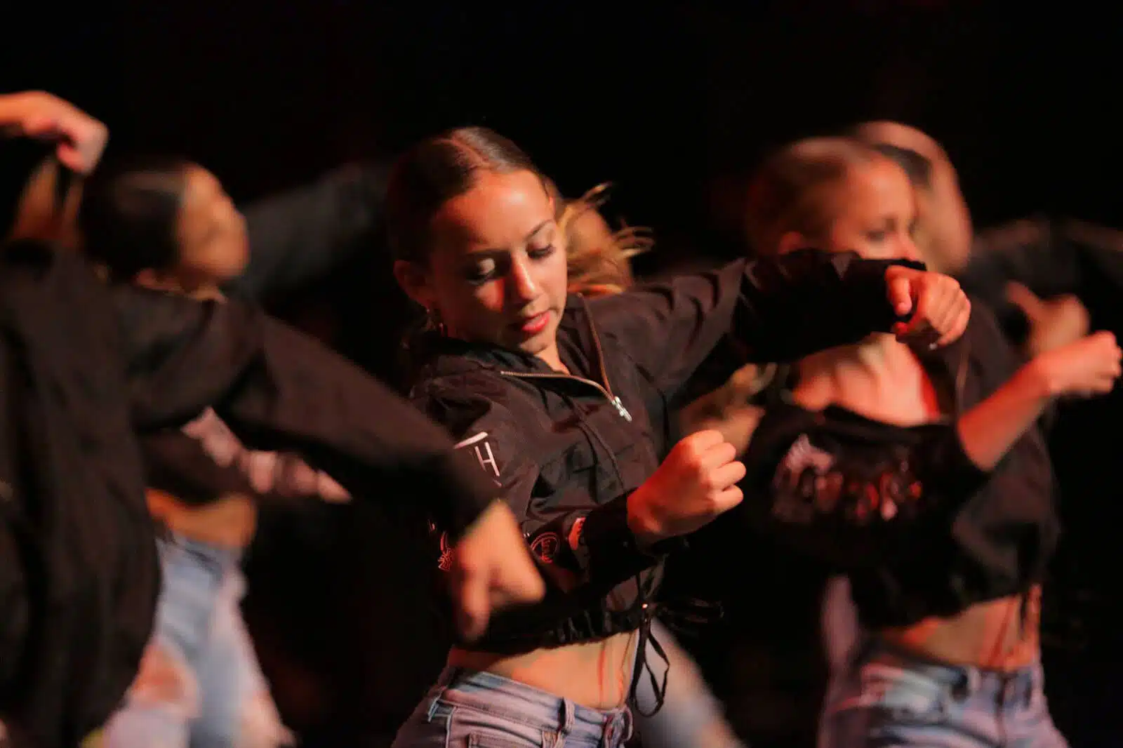 Empire Dance Center team performing a dramatic routine in black costumes on stage.