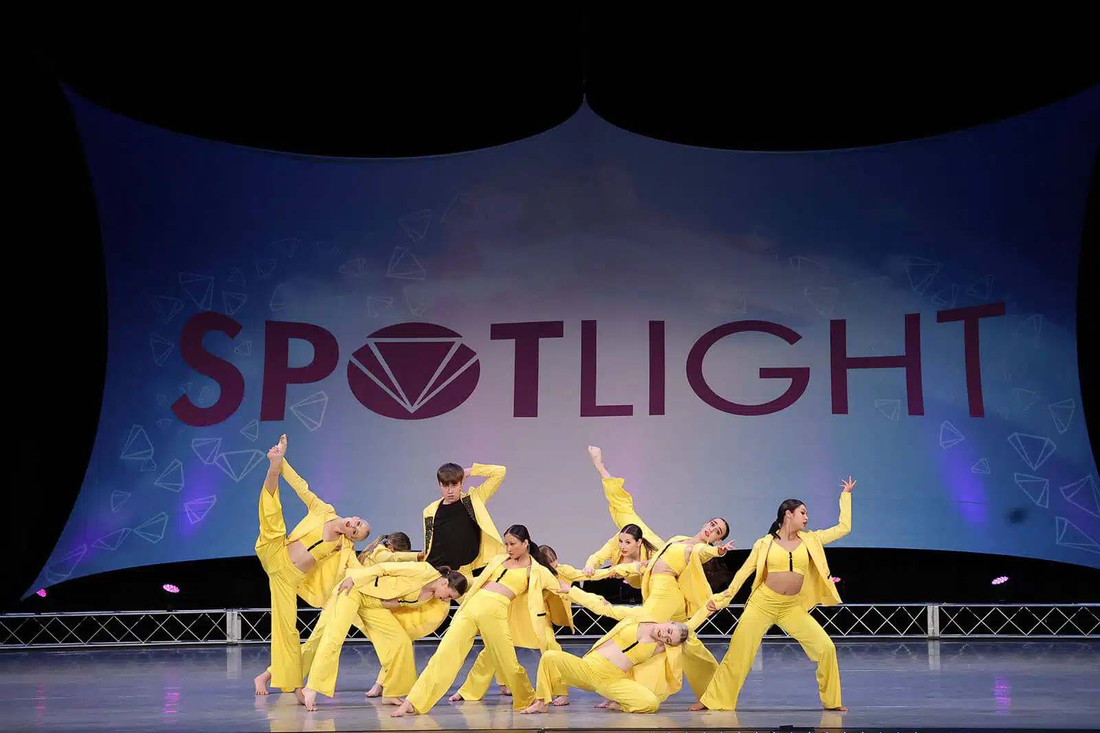 Empire Dance Center team in yellow costumes performing on the Spotlight stage.